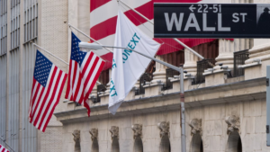 Указатель Wall Street и американские флаги у фасада Нью-Йоркской фондовой биржи