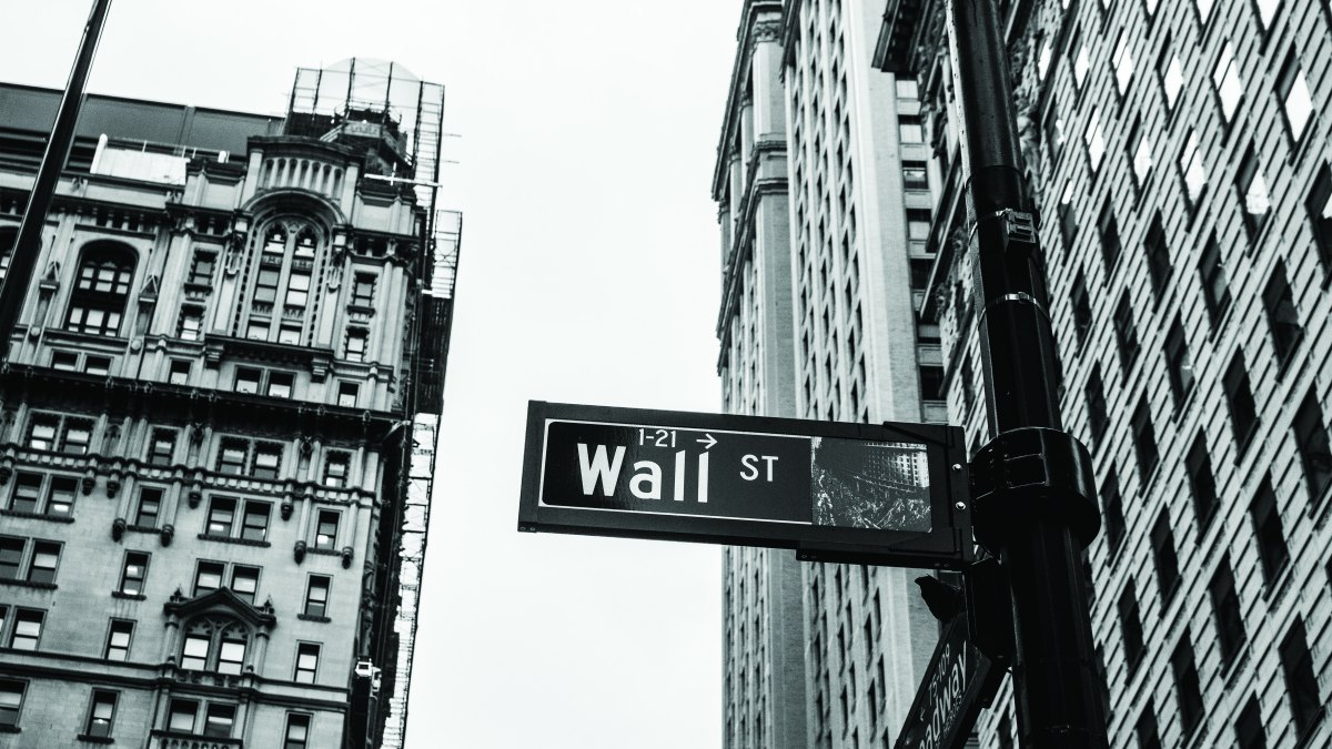 Уличный указатель Wall St на фоне небоскрёбов финансового квартала Нью-Йорка, чёрно-белый снимок